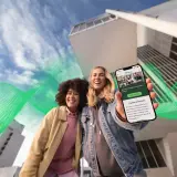Dwie uśmiechnięte kobiety trzymają telefon z informacją o karierze w Fortum. Czy się opłaca? Sprawdź sam!
