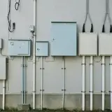 Zestaw skrzynek elektrycznych i rur na ścianie. Zastanawiasz się, ile trwa ponowne podłączenie prądu Enea?