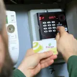 Jak doładować licznik przedpłatowy bez karty PGE? Osoba wkłada kartę Energa do terminala licznika, by zasilić konto.