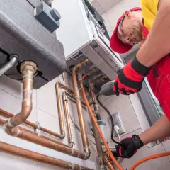 Instalator naprawia piec gazowy. Uniknij kary za nie przepisanie licznika gazu, dbając o sprawność instalacji.
