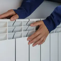 Dłonie na grzejniku, zmartwienie o rosnące ceny gazu.