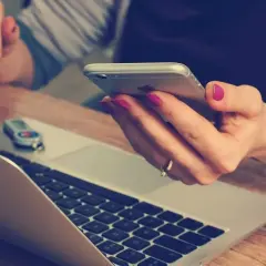 Kobieta z różowym lakierem na paznokciach trzyma telefon, obok laptopa. Szybko dzwoni na infolinię Energa Obrót, by rozwiązać sprawę.