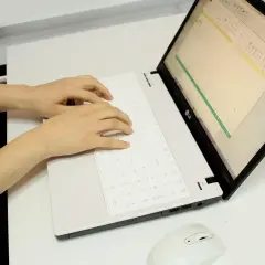 Ręce piszą na klawiaturze laptopa, przygotowując tauron wypowiedzenie umowy online.