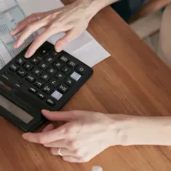 Ręce liczą na kalkulatorze przy dokumentach podatkowych. Dowiedz się, jak zrezygnować z opłaty handlowej PGE.