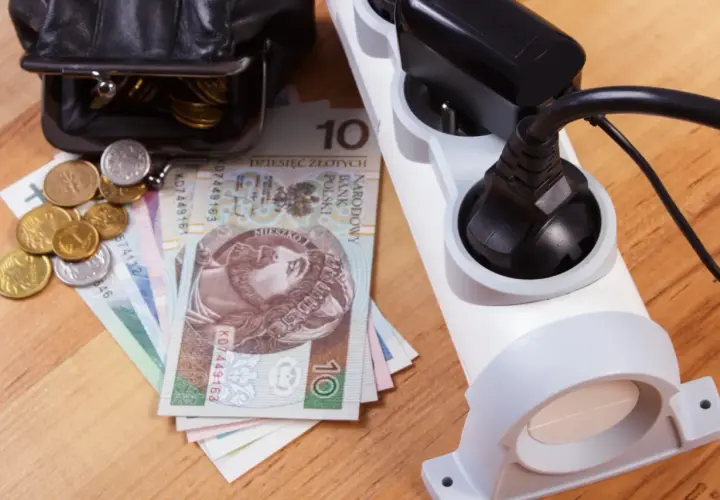 Portfel z pieniędzmi i monety obok listwy zasilającej. Rosnące ceny prądu to spory dodatek do rachunków.