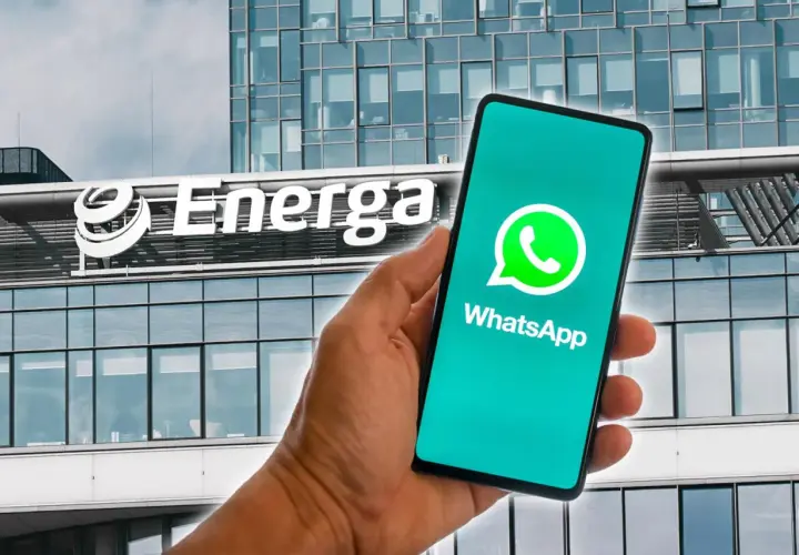 Dłoń trzyma smartfon z logo WhatsApp na tle budynku Energa. Możliwość zawierania energa umowy przez telefon.