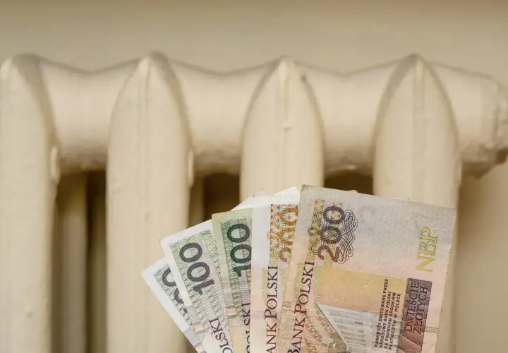Pieniądze w ręku na tle grzejnika. Czy to zapowiedź bonu energetycznego 2026?