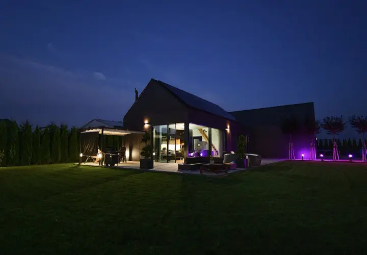 Nowoczesny dom pasywny nocą, z oświetlonym ogrodem i tarasem. Cena takiego domu jest inwestycją w przyszłość.