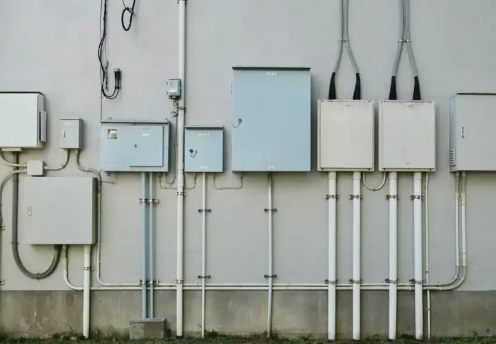 Zestaw skrzynek elektrycznych i rur na ścianie. Zastanawiasz się, ile trwa ponowne podłączenie prądu Enea?