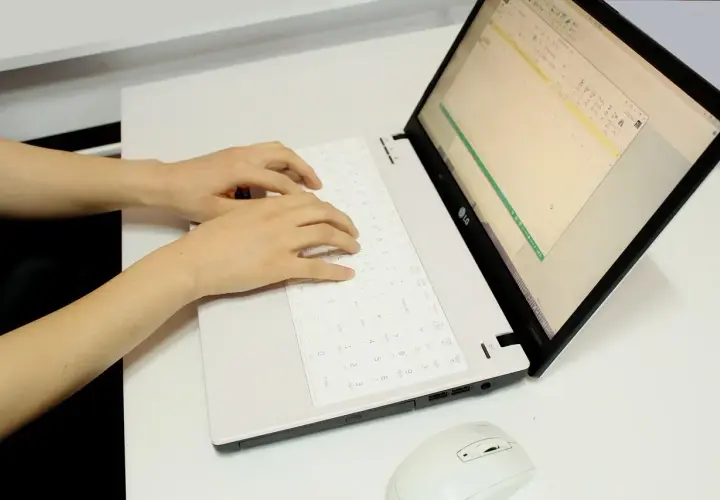 Ręce piszą na klawiaturze laptopa, przygotowując tauron wypowiedzenie umowy online.