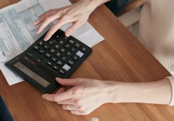 Ręce liczą na kalkulatorze przy dokumentach podatkowych. Dowiedz się, jak zrezygnować z opłaty handlowej PGE.