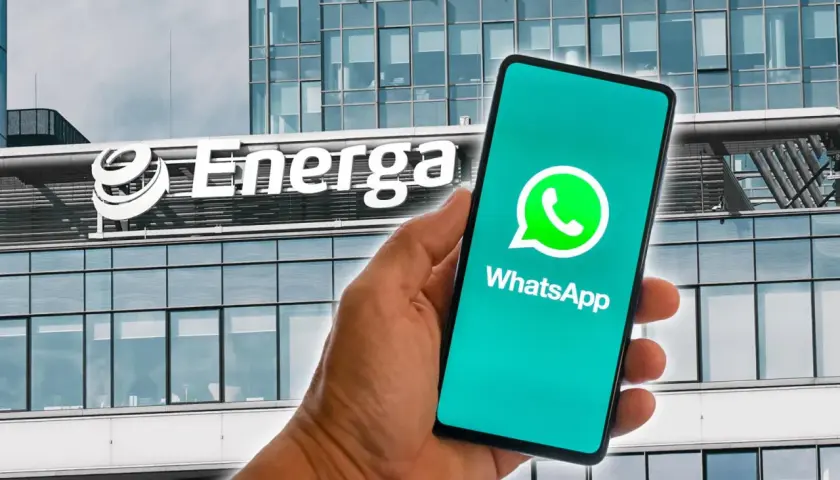 Dłoń trzyma smartfon z logo WhatsApp na tle budynku Energa. Możliwość zawierania energa umowy przez telefon.