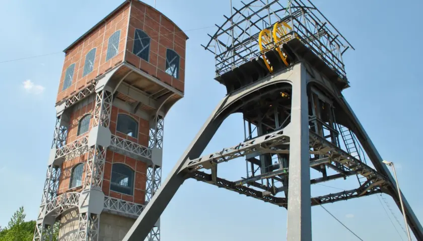 Dwie wieże kopalniane, jedna ceglana, druga metalowa z kołem, tworzą futurystyczny grawitacyjny magazyn energii.