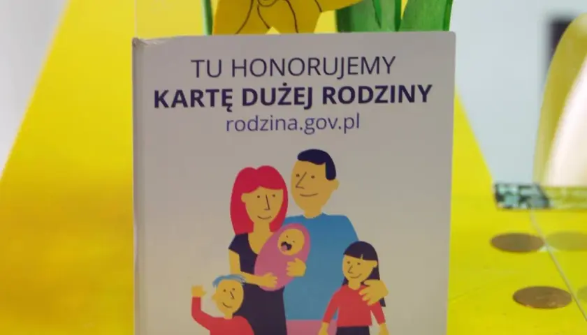 Grafika z napisem "Tu honorujemy Kartę Dużej Rodziny" i rysunkiem rodziny.