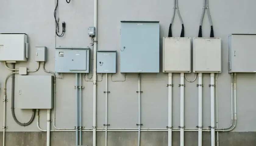 Zestaw skrzynek elektrycznych i rur na ścianie. Zastanawiasz się, ile trwa ponowne podłączenie prądu Enea?