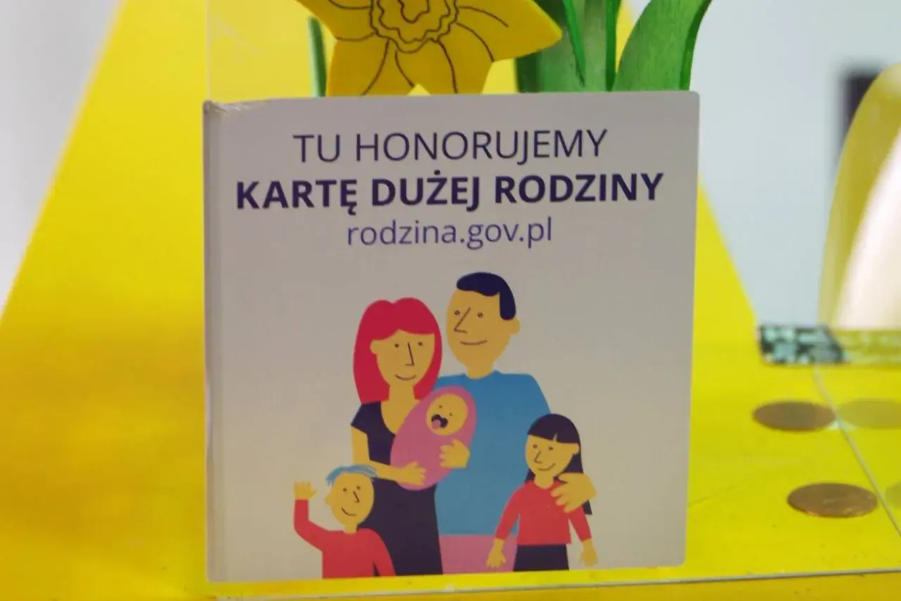 Grafika z napisem "Tu honorujemy Kartę Dużej Rodziny" i rysunkiem rodziny.