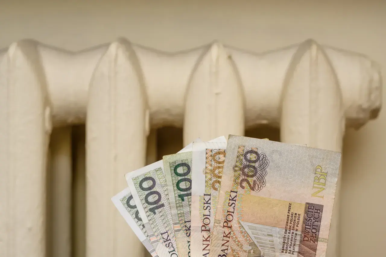 Pieniądze w ręku na tle grzejnika. Czy to zapowiedź bonu energetycznego 2026?