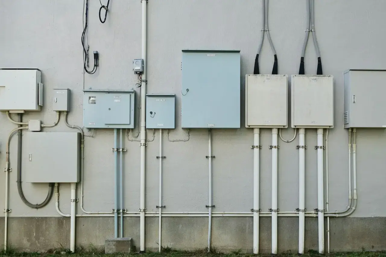 Zestaw skrzynek elektrycznych i rur na ścianie. Zastanawiasz się, ile trwa ponowne podłączenie prądu Enea?